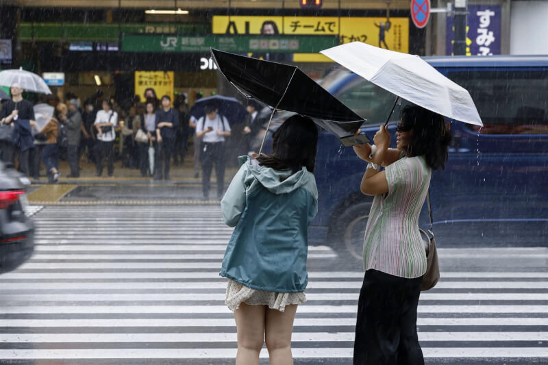 日本東京7日下大雨，JR新宿站前人們在暴雨中等待過馬路。 （共同社）