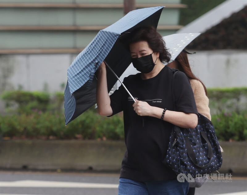 圖為台北市信義區街頭民眾撐傘遮擋雨勢。（中央社檔案照片）