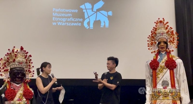 雷昇傳藝劇團執行總監王昇揚（右1）手持劇團守護神「田都元帥」尊像，向波蘭國家民俗博物館方介紹台灣民間信仰典故與陣頭文化。 中央社記者鄭淨伃華沙攝　115年9月10日