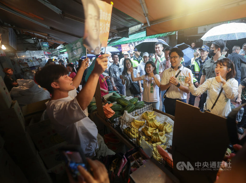 民進黨台北市長參選人沈伯洋（前右2）11日赴大安區臨江市場掃街拜票，有攤商揮舞沈伯洋旗幟，為他加油打氣。中央社記者裴禛攝　115年9月11日