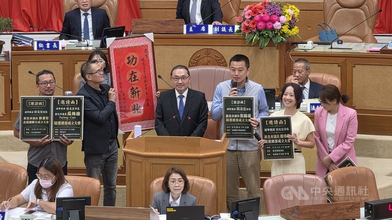 新北市長侯友宜（2排左3）14日列席新北市議會備詢時，意外獲民主進步黨籍新北市議員戴瑋姗（2排右2）等贈送「功在新北」鏡屏，並邀侯友宜出席各自的競選總部成立大會。中央社記者王鴻國攝　115年9月14日