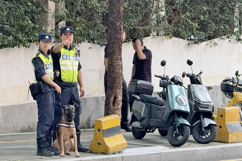 中國深圳警察帶著警犬17日在日人學校附近密切關注來往行人。（共同社）