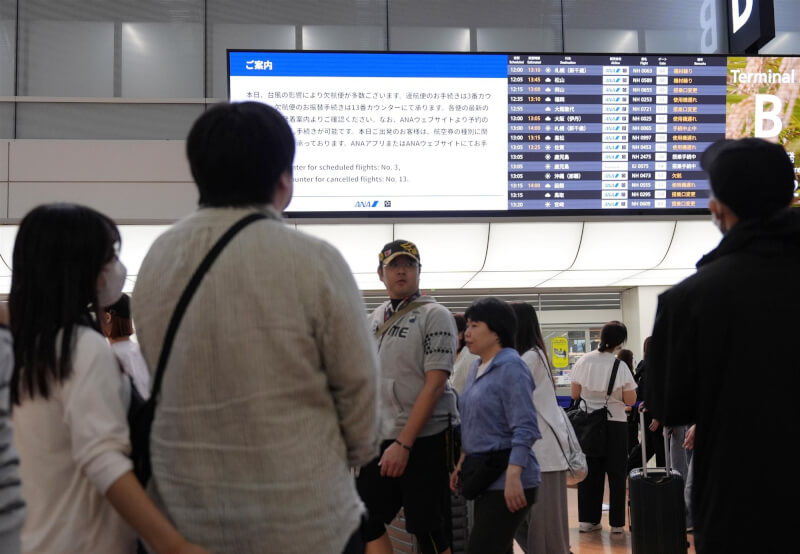颱風杜鵑朝日本東京逼近，21日至少275個航班取消。圖為民眾在東京羽田機場查看航班資訊。（共同社）