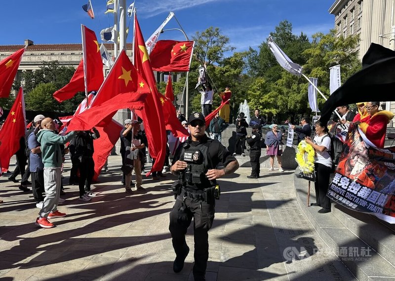 民主示威團體與中國僑團在美國國家檔案局前對峙揮舞旗幟,警方隔開雙方群眾。中央社記者廖漢原華盛頓攝 115年9月26日