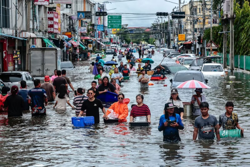 泰國民眾27日涉水通過淹水地區。（路透社）