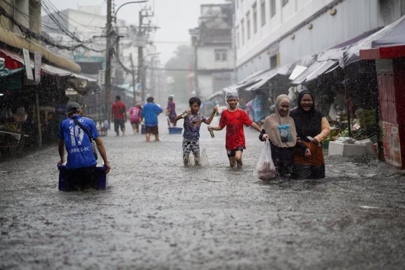 泰國暴雨成災,曼谷一處市場28日淹水,民眾涉水而過。(路透社)