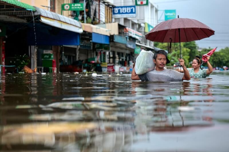 泰國受豪雨影響，曼谷及25個府傳淹水災情。圖為27日曼谷民眾涉水走在街頭。（路透社）