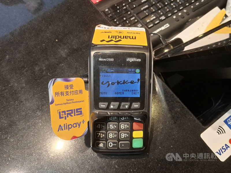 印尼購物中心店家也使用印尼標準式QR支付碼（QRIS）提供非現金支付。圖為一家購物中心店家的電子收款設備，標示「接受所有支付應用程式」，並列有QRIS與支付寶（Alipay）標誌。中央社記者羅薇佳雅加達攝　115年9月30日