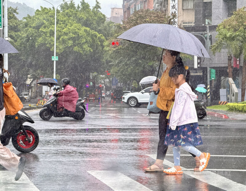 5日迎風面轉有雨、有較大雨勢，氣溫將明顯下降。圖為台北內湖區街頭，民眾撐傘過馬路。（中央社檔案照片）