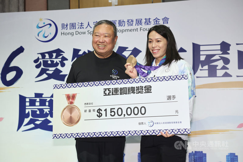 「舉重女神」郭婞淳（右）在名古屋亞運女子61公斤級獲得銅牌，5日出席宏道運動發展基金會慶功餐會，獲董事長林鴻道（左）頒發新台幣15萬元獎金。中央社記者王飛華攝　115年10月5日