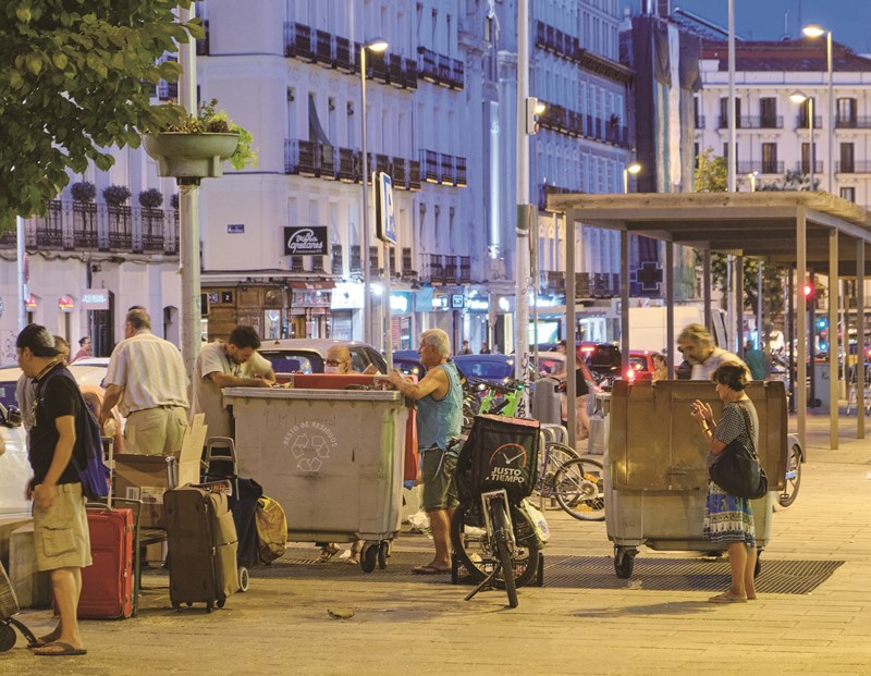 入夜後的馬德里街頭，有愈來愈多需要食物的貧困弱勢家庭，聚集在超市的垃圾桶前，翻找被丟棄的食物。（中央社胡家綺）