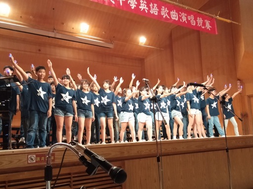 由國一1班演唱電影歌喉讚(Pitch perfect)2的主題曲Flashlight,國一學生展現活潑可愛的一面。而練習過程中,英文科陳美君老師、孫韻玉老師;音樂科張意艷老師及導師鄧喻心齊心協力幫助學生們練習,從最基本的背歌詞開始督促,加上動作編排、搭配服裝巧思及人手一盞LED燈,讓整首歌曲的意境在嘹亮的歌聲、整齊的動作與明暗閃爍的燈光中貫串融會,展現對生命的期許與熱誠,表演結束後,評審給予「團隊默契佳」、「咬字清晰」、「表演動作整齊一致」等高度評價,從中可見演出精彩。