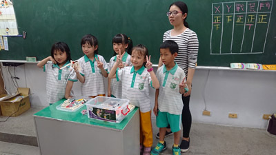 員林國小學童拿著自己組的竹槍與大葉大學企管系大三生莊怡瑄(後排)開心合影