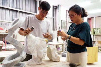 大葉大學造藝系廖秀玲主任(右)指導李伯元(左)創作石雕