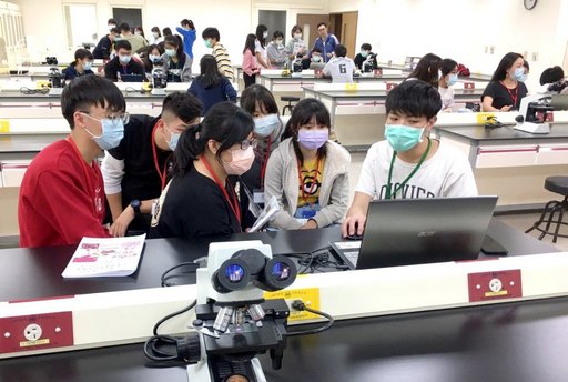 輔導員藉由顯微鏡組織切片,向高中生介紹人體各器官的組織結構。(義守大學提供)