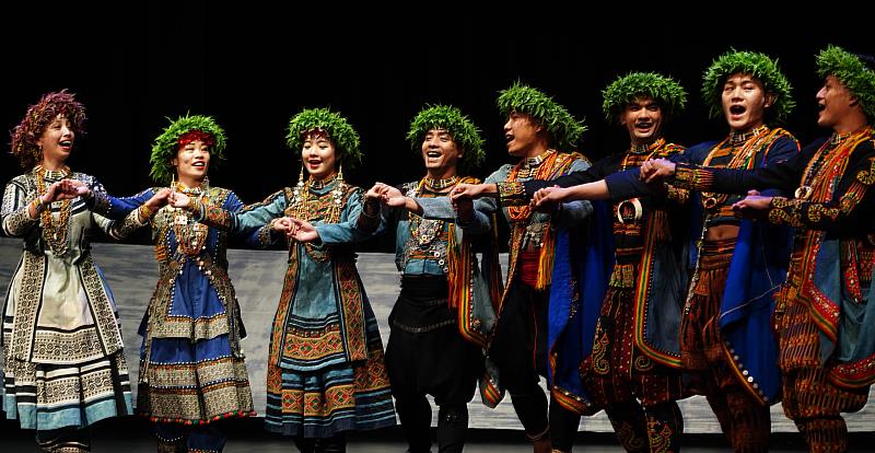 蒂摩爾古薪舞集舞者們穿著華麗的排灣族傳統服飾，手牽著手一邊吟唱古謠一邊跳舞。