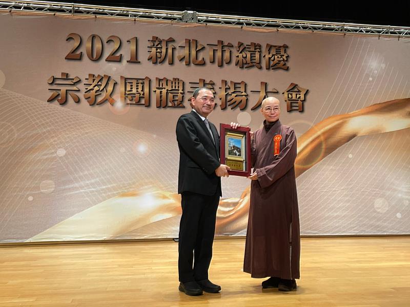 2021新北市績優宗教團體表揚大會，市長侯友宜（左）頒發獎牌給靈鷲山無生道場，由靈鷲山榮譽董事會總會秘書長妙用法師（右）代表領獎。（圖由靈鷲山佛教教團提供）