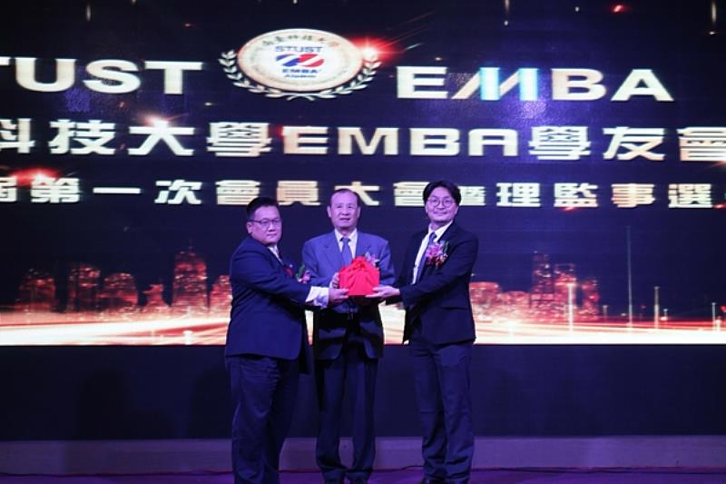 南臺科大EMBA學友會第十一 屆理事長交接典禮，校長盧燈茂(中)監交下，由第十屆卸任理事長林昆鋒(左)將印信交接予第十一屆新任理事長黃志煌(右) 合影留念。