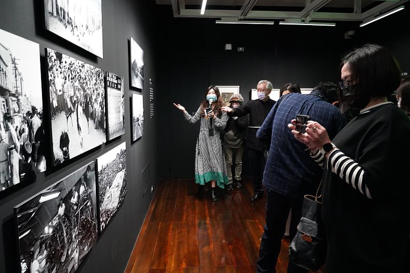 展覽策劃人蔡旻螢為開幕式貴賓介紹秦凱新聞攝影作品。