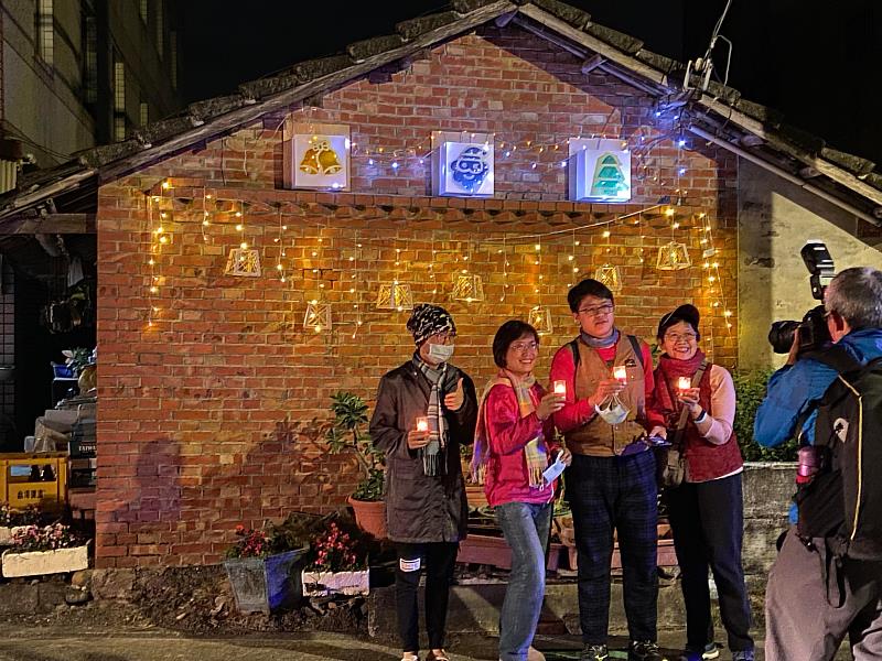 古坑麻園村歲末送舊迎新，與南華師生攜手舉辦「麻園平安節」，村民與山牆燈飾造景合影。