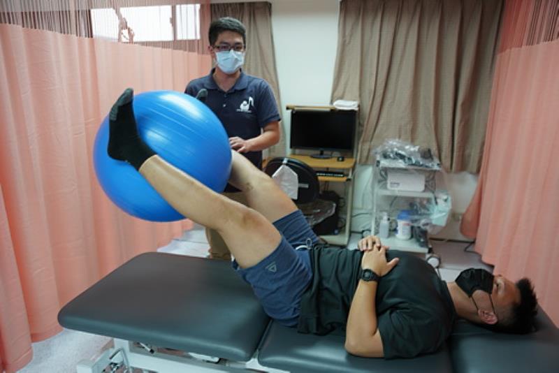 游先生在物理治療師指導下以瑜珈球運動復健的情形。