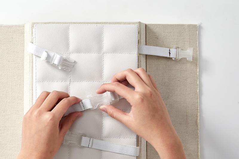 作品書殼以堂服為概念，並採麻布包裹產生皺褶感，連結主體和書殼的彈性帶與安全扣，展現出被束縛與禁錮的枷鎖，設計十分鮮明。