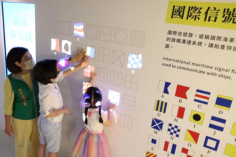 張榮發基金會執行長鍾德美教導孩子如何以觸控方式，讓光雕牆上的信號旗飄揚起來！