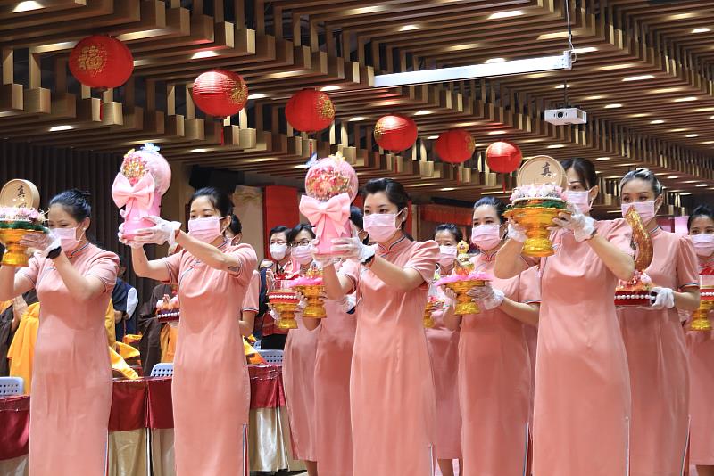 「全球獻供」主場隊伍身著粉橘色旗袍，以花、果、燈、經文、寶瓶、海螺、舍利塔等十供養，莊嚴會場。（圖由靈鷲山佛教教團提供）