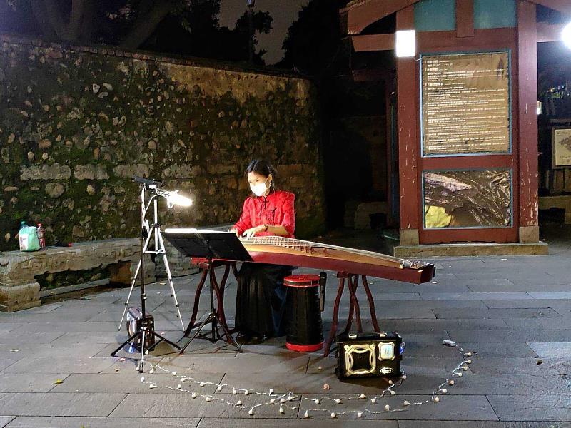 街頭藝人於林家花園門口廣場彈奏古箏，讓民眾沉浸在悠揚樂音中。