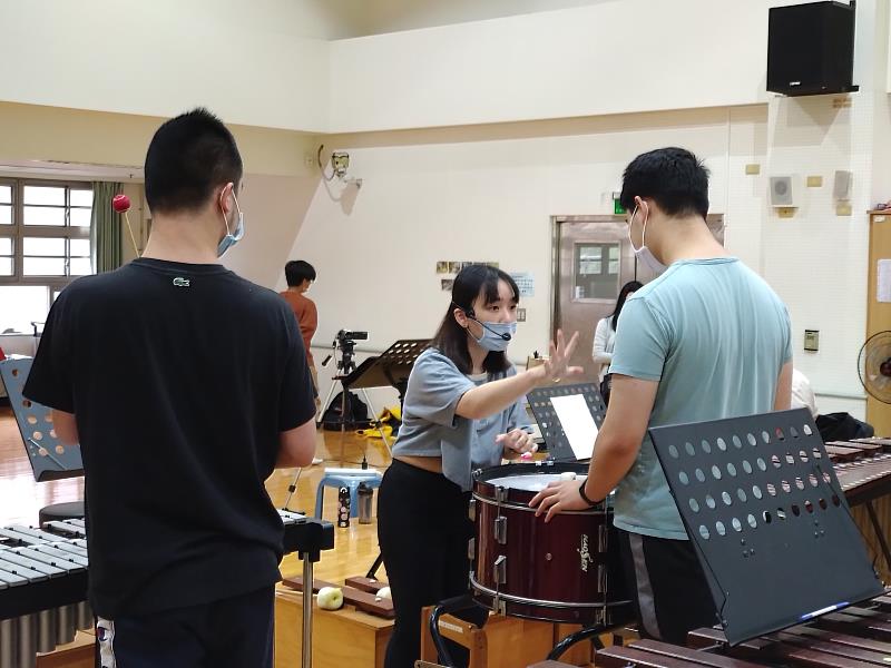 老師指導打擊大鼓的同學演奏的方法