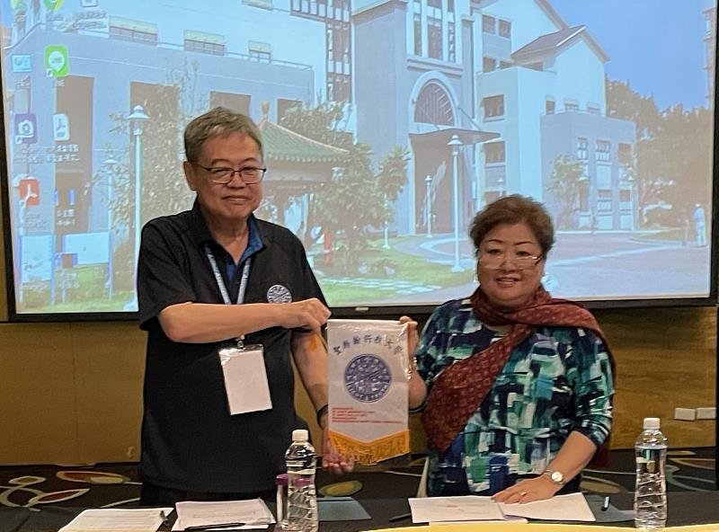 張文宇校長（左）致贈聖約翰科大校旗給陳明和董事長夫人Ka Yee (Nancy),CHEN，感謝其參與贊助「入學即就業」計畫。