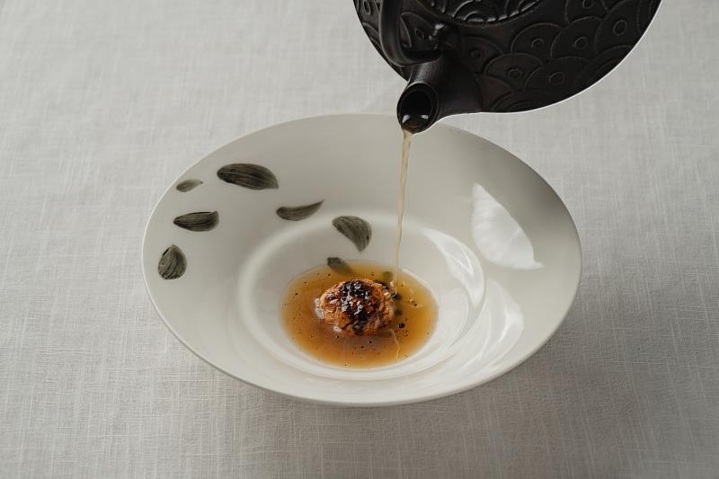 「葉落山間湯暖春」的雞肉丸以翅小腿加入雞軟骨增添些許嚼勁，再將味道鮮美的老母雞湯倒入碗中，黑蒜油於表面形成如水墨般的圓點，與書畫家手繪的葉子相互呼應。