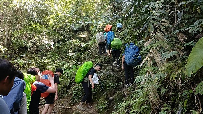 背負重裝走在原始山林路徑。