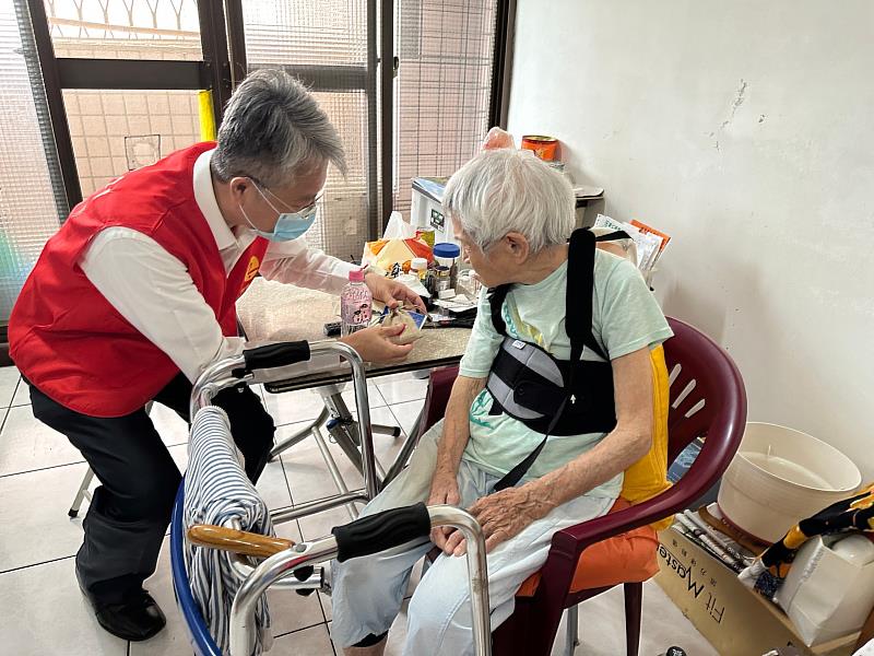 靈鷲山慈善基金會副執行長陳世人（左）拿佛水、祈福香囊、手工佛足皂，關懷獨居長輩。（圖由靈鷲山佛教教團提供）