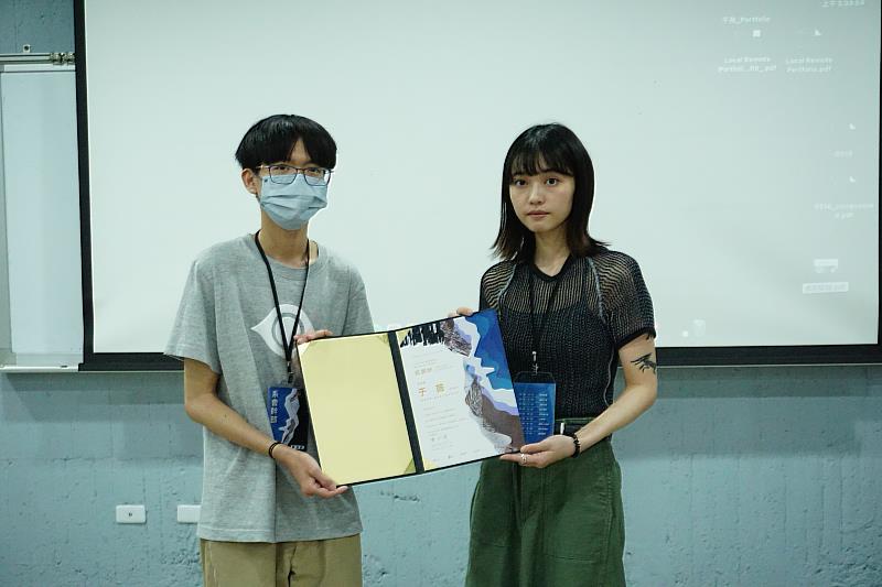 視傳系系學會會長二年級李坤益 (左)頒發感謝狀贈予設計師于薇(右)