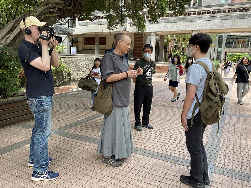 德國媒體記者(左一)於校園取景，圖為何浩哲老師(中)與學生互動。