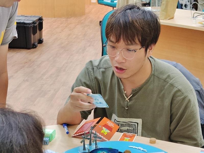 桌遊遊玩過程，參與同學正在念誦遊戲事件卡的內容。