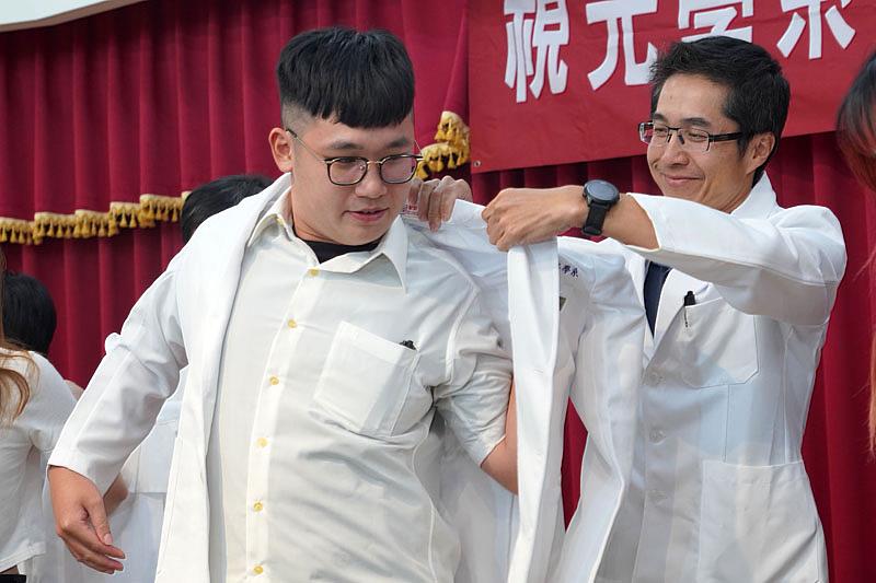 大葉大學視光系許又文主任(右)為學生穿上白袍