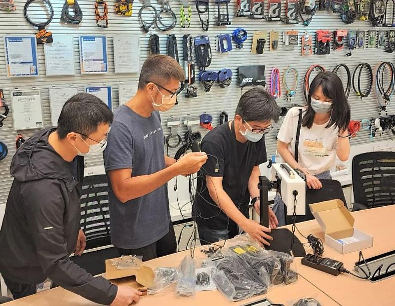 職場導師(左2)帶領承欣(右1)和同事們進行新產品零件測試