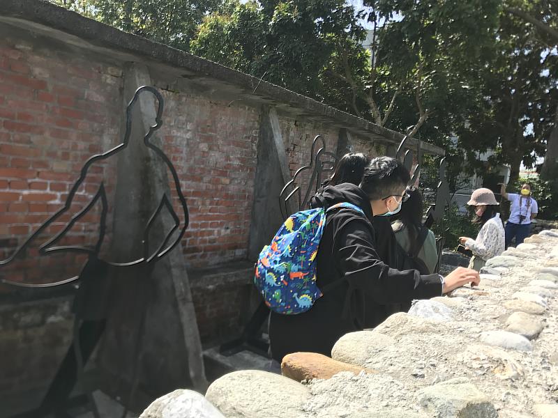 學生聽取光華城鄉發展協會監事林家菱（右數第一人）訴說光華村的老建築與故事。