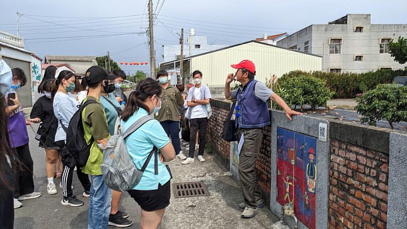 吉貝耍「部落學堂」導覽員徐永泰向學生解說陶板牆上飛番賽馬的故事