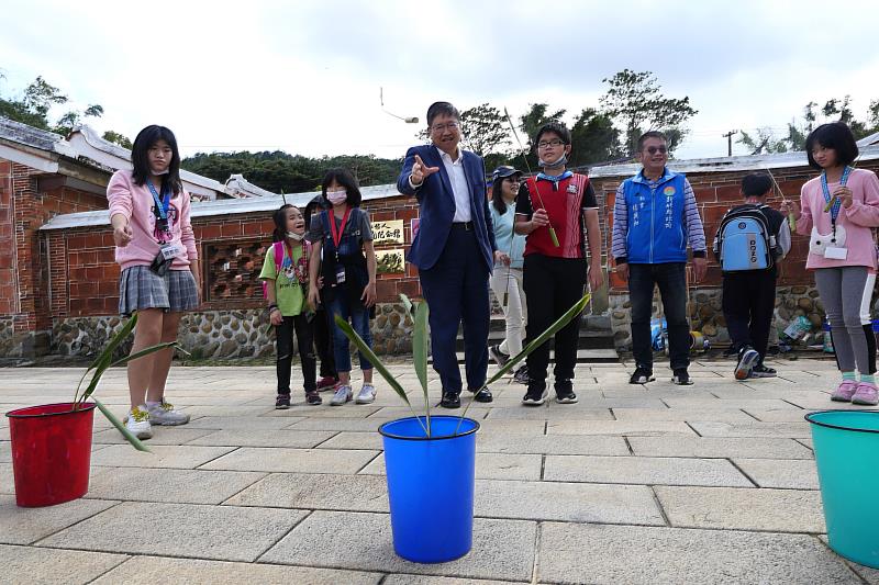 縣長楊文科(中)與孩子體驗丟月桃炸彈(2021年文學小旅行照)