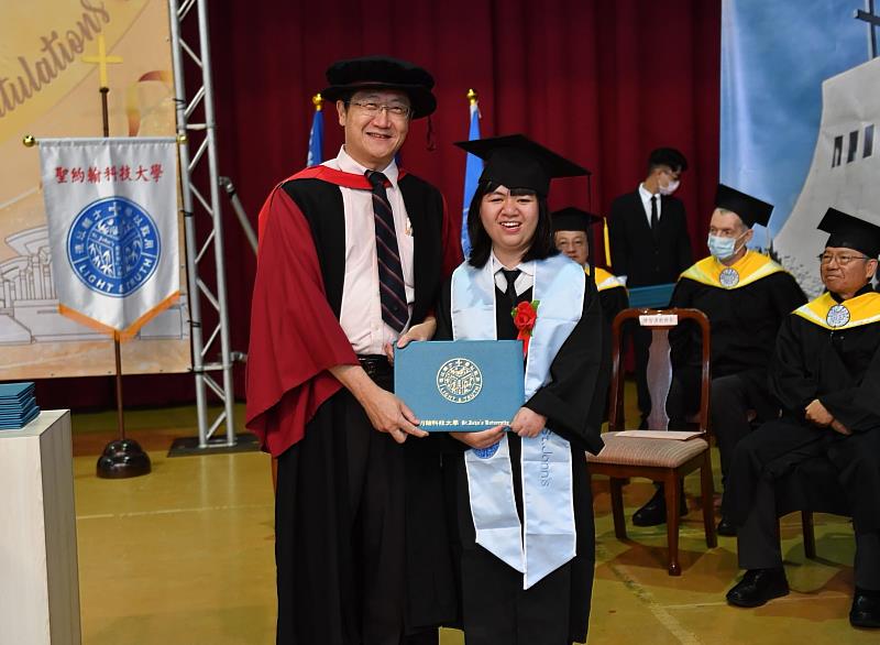 蔡路得順利完成大學學業，從陳智湧教務長手上領取畢業證書。
