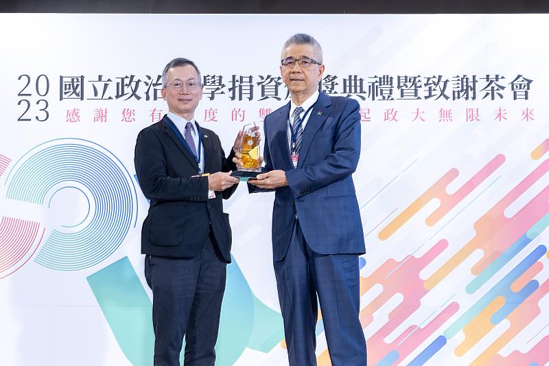 信義企業集團創辦人周俊吉（右）從政大校長李蔡彥手中接下感謝獎座。