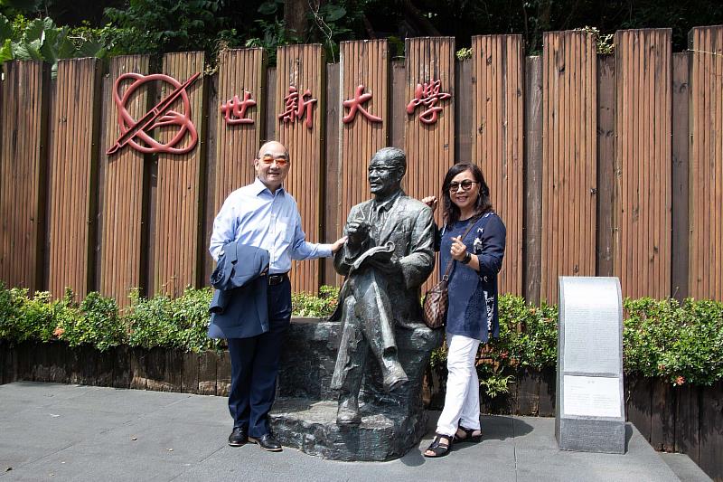 愛護母校的陳家麒與妻子鄭淑芬在成舍我雕像留下紀念。（世新大學提供）
