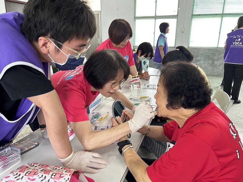 口腔衛教時，志工仔細說明，並實際操作。（圖由靈鷲山慈善基金會提供）