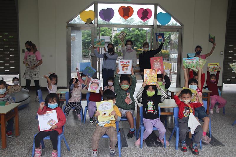 孩子們高舉手中的繪本，與師長一同留下合影紀念，期望孩子們能夠透過閱讀來陪伴他們成長和認識這個世界。