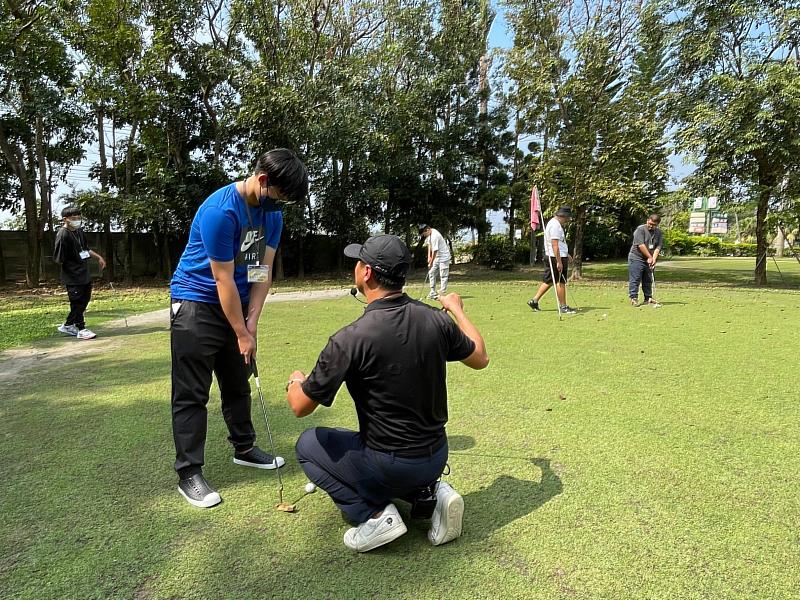 教練耐心修正學生推桿姿勢，指導學生高爾夫推桿技巧