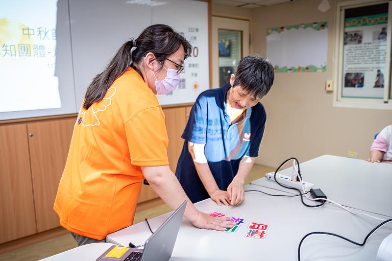 職能治療師楊沛璇(左)透過認知團體課程搭配自製圖卡，幫助智能障礙者反覆學習。