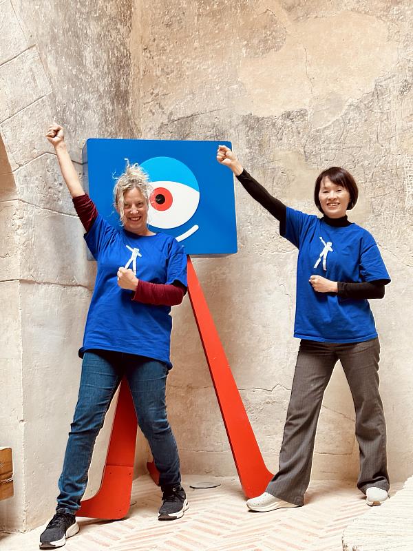 文化機構Mónica Ibañez總監(左)與曾惠青老師穿著視傳系服與影展象徵標誌在播映會的古堡中合照